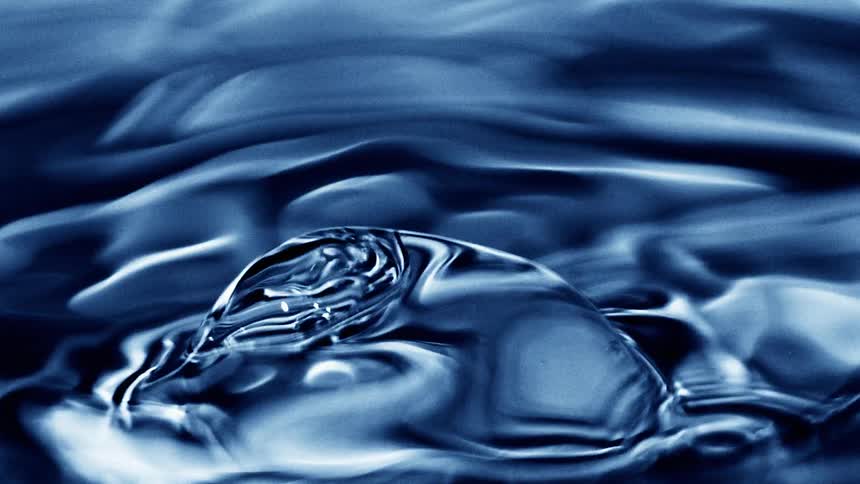 Blue water surface with small ripples and an emerging bubble