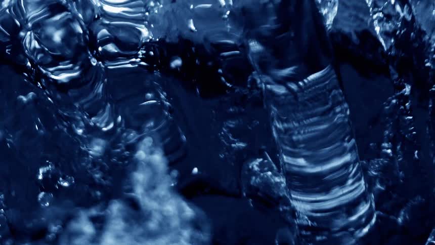 Water flows rapidly creating a ripple effect as it disturbs the surface with continuous motion