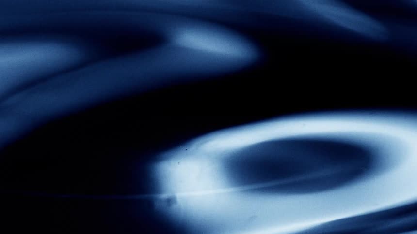 Blue liquid surface forms gentle waves and light reflections