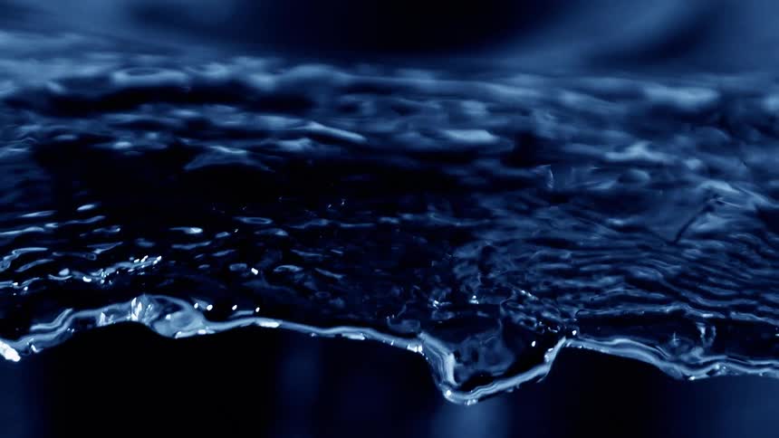 Layer of dark blue water moves with luminous reflections on the surface