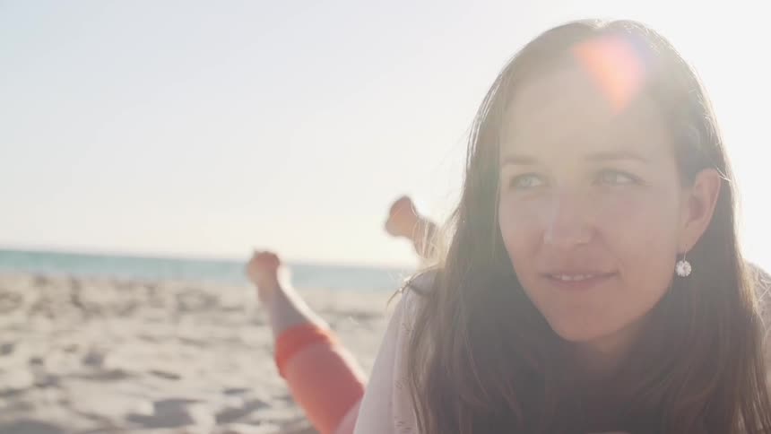 Woman smiling as she lies on the sand