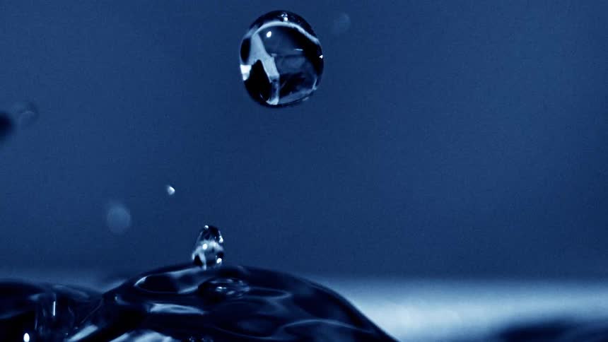 Water bubbles rise and burst forming droplets that ripple across the surface of a large body of water