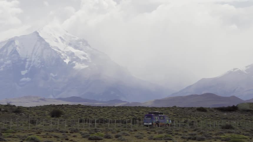 A van drives with snowy mountains in the distance