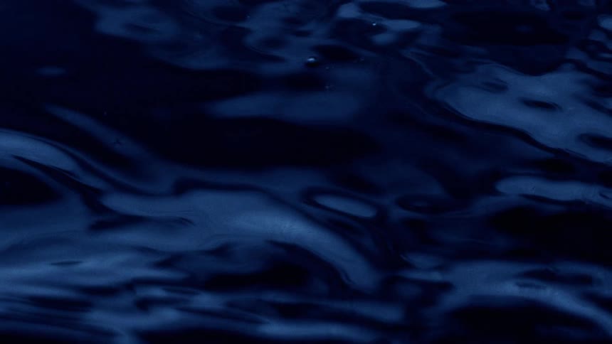 Dark blue water surface with gentle reflections and rippling motion