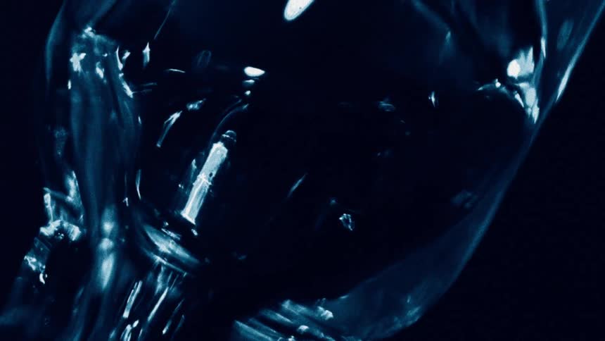 Liquid flows through a bottle in a dark setting illuminated by a focused beam of light