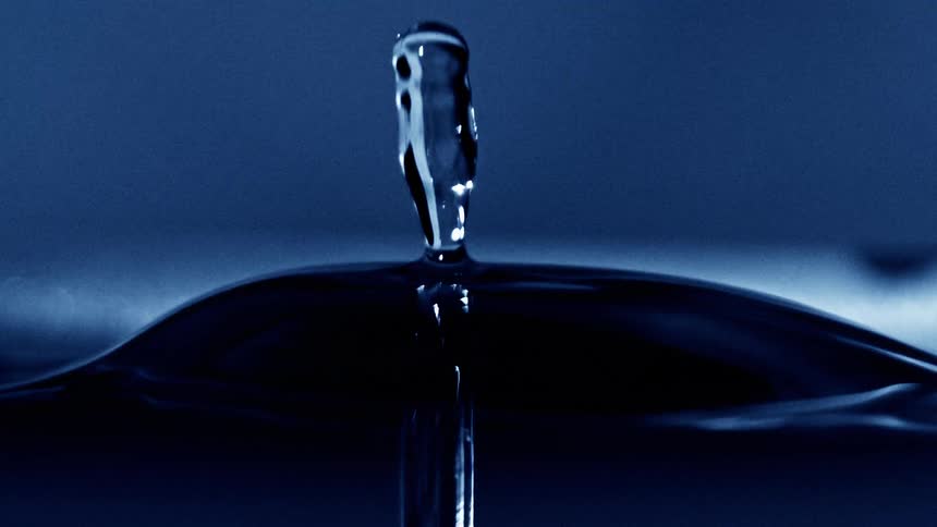 Blue water droplets collide and create a splash on the liquid surface
