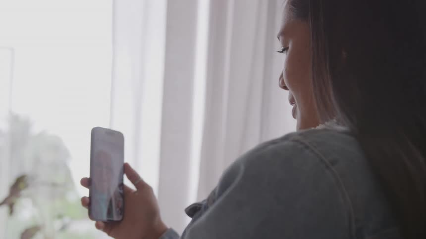Woman smiles while talking during a video call on her smartphone in the daytime