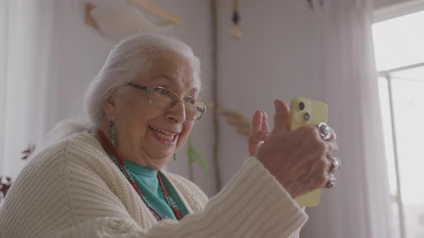 Elderly woman smiling and waving during a video call