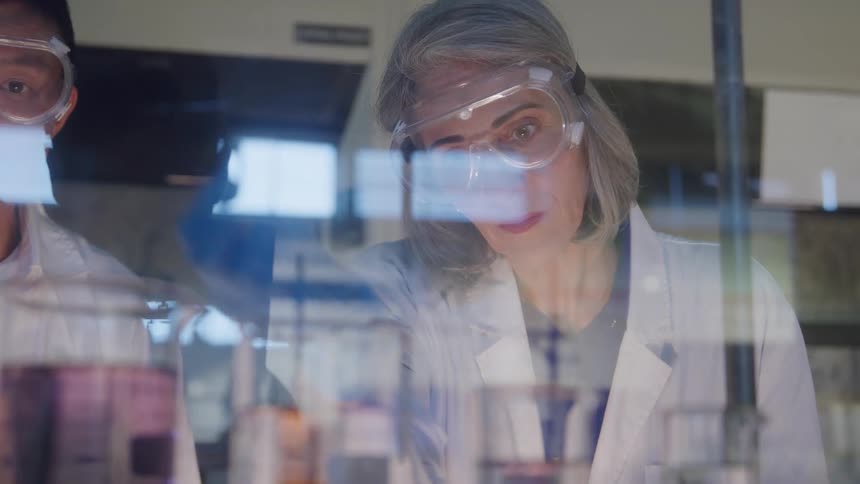 Man and woman conducting an experiment in a laboratory setting with scientific equipment and containers on the bench