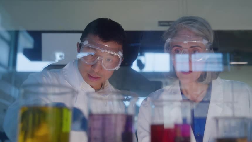 Two scientists observing tubes with colored liquids in a laboratory