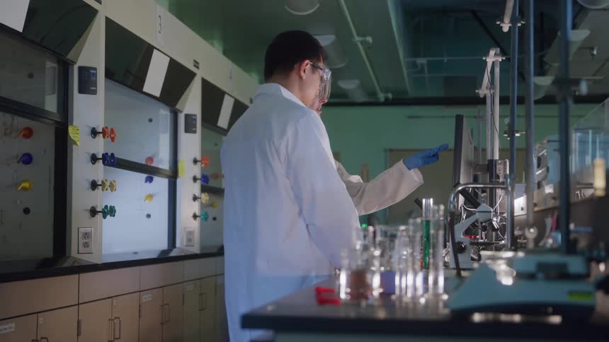 Two scientists working together in a laboratory with equipment and glassware on the bench