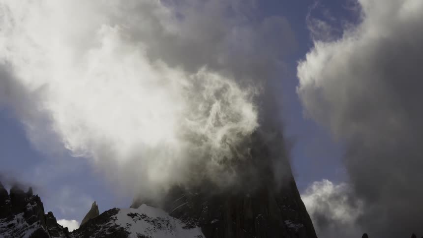 Clouds form around a rocky mountain peak