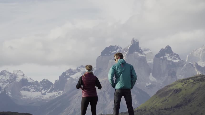 Two people stand and look out at mountains