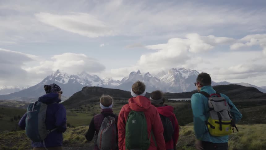 Five hikers are looking at the snow covered peaks in the distance