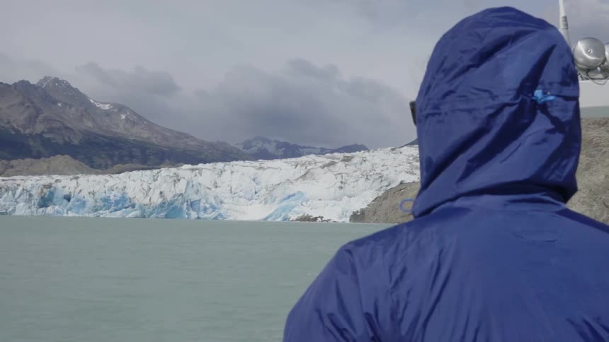 Person on a boat looks at the water and mountains