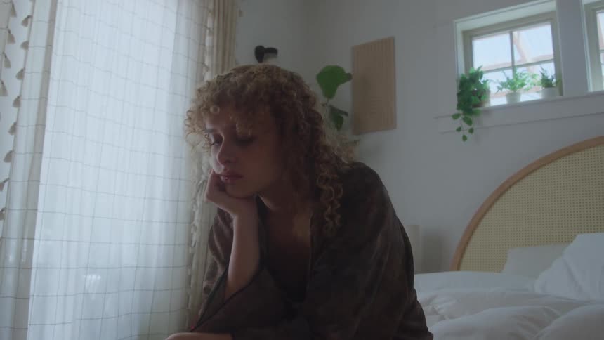 A woman sits in a bedroom
