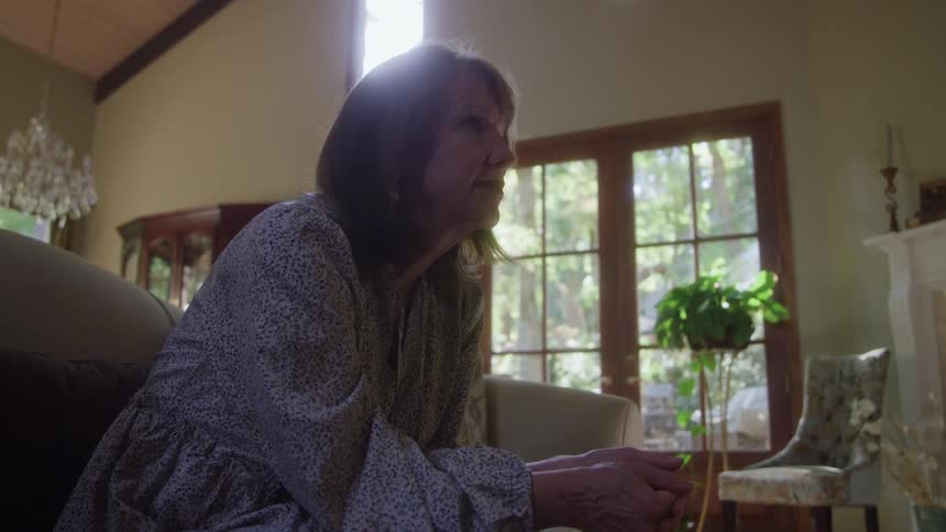 The woman is sitting on her couch at home