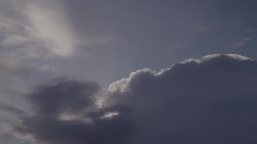 Sky with dark and light clouds sidelit by sunlight during a transitional time of day