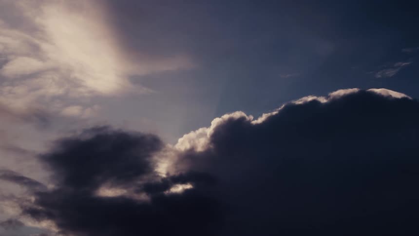 Dark and light clouds contrast in the sky at dusk with sunlight illuminating the upper edges