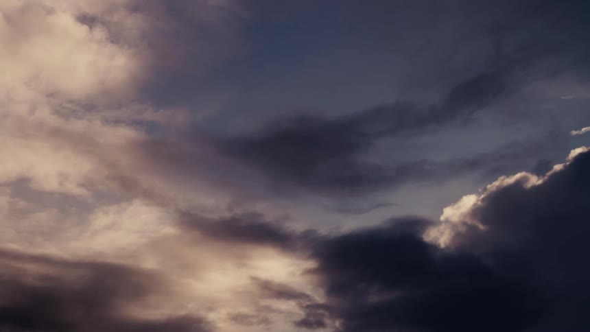 Sky covered with dense clouds in golden and dark blue tones at dusk