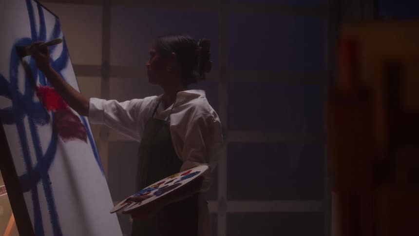 A woman paints on a canvas