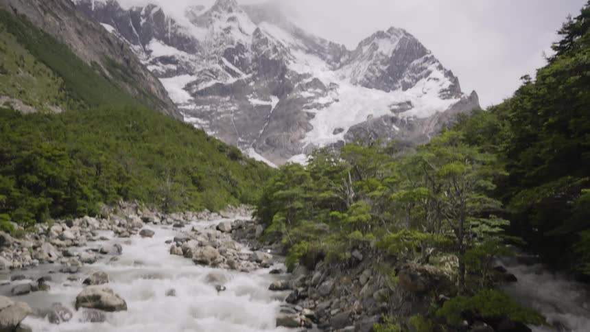 Rapids run in front of a snow covered mountain