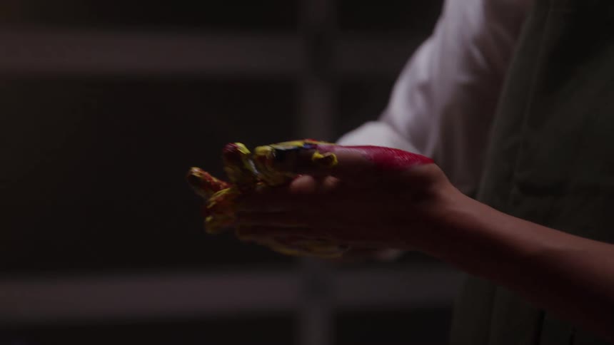 An artist rubs paint across their palm after a painting session hands stained with vibrant colors from the creative process