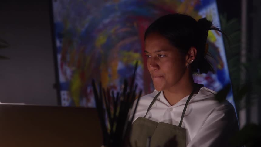 Close up of a young black female artist painting a canvas in an art studio