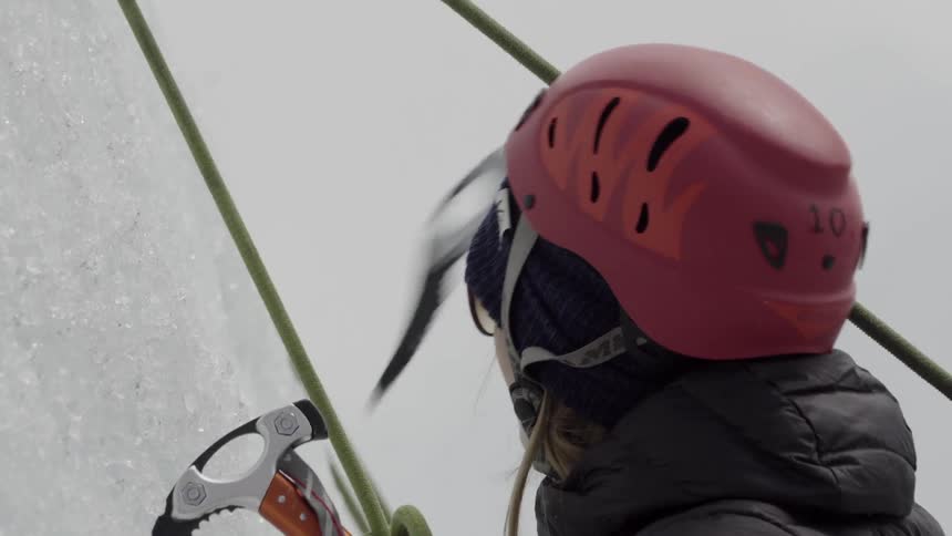 Woman uses picks to climb up an icy mountain