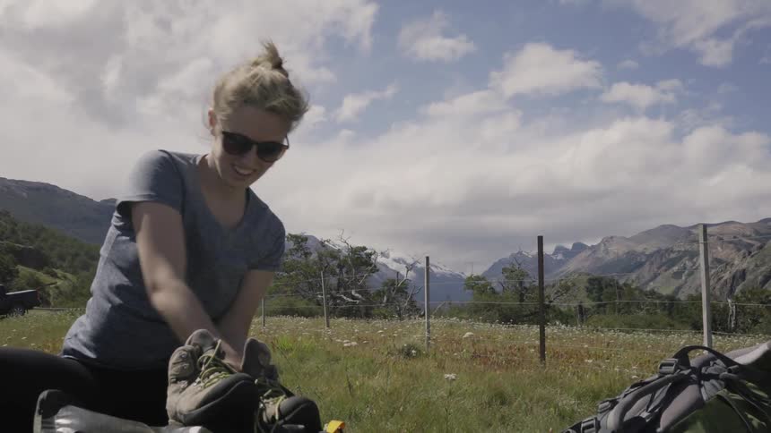 A woman puts insoles inside hiking boots in the wilderness