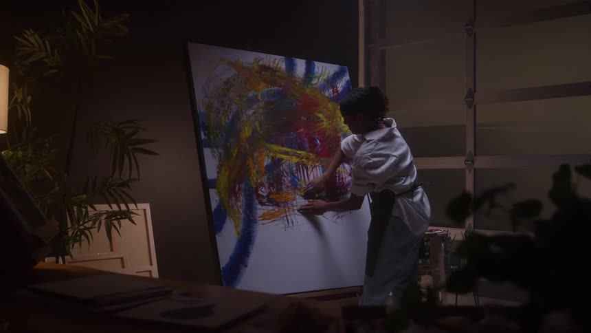 The woman drags her hands across the canvas as she paints
