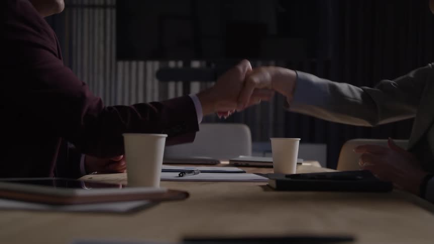 Two people in the office talk and shake hands