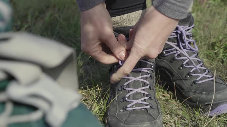 Person tying their hiking boots outside on windy day