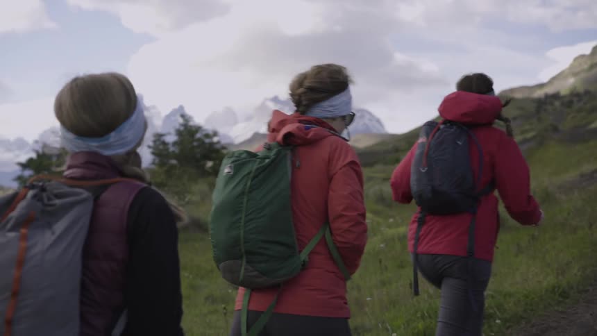 Hikers climb up a grassy mountainside