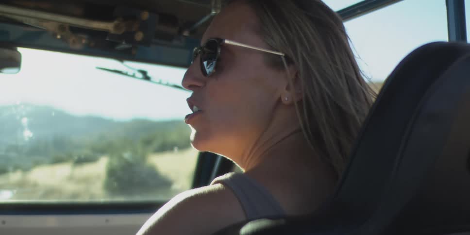 Female passenger smiles and talks to the driver during a road trip on a summer day