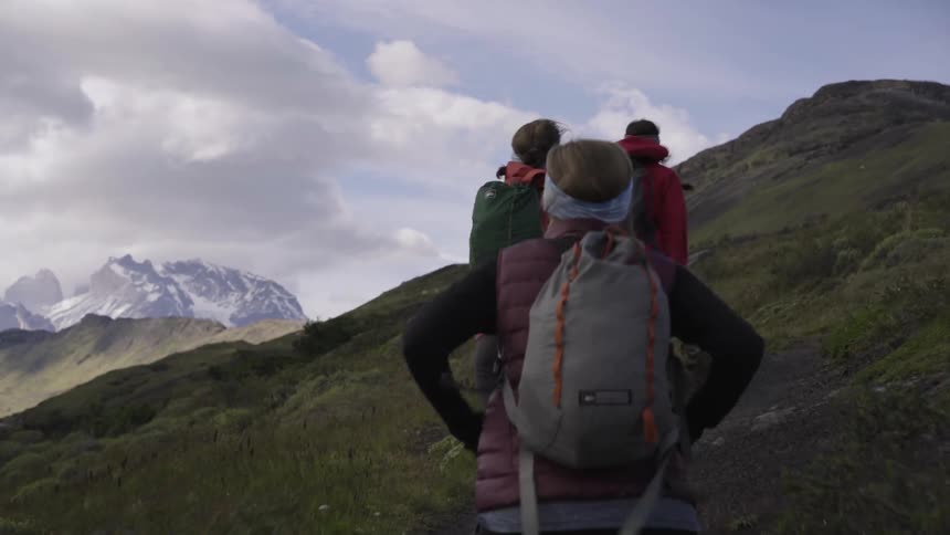 Hikers walk up a hill on a windy day