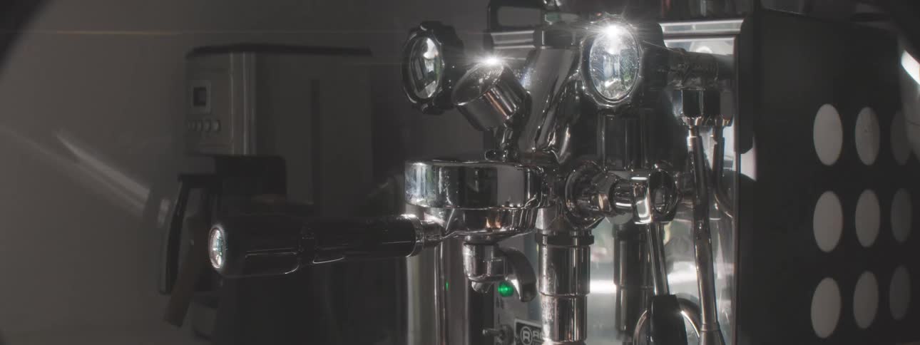 A man places freshly ground coffee beans into an espresso machine preparing to brew a rich aromatic cup of coffee