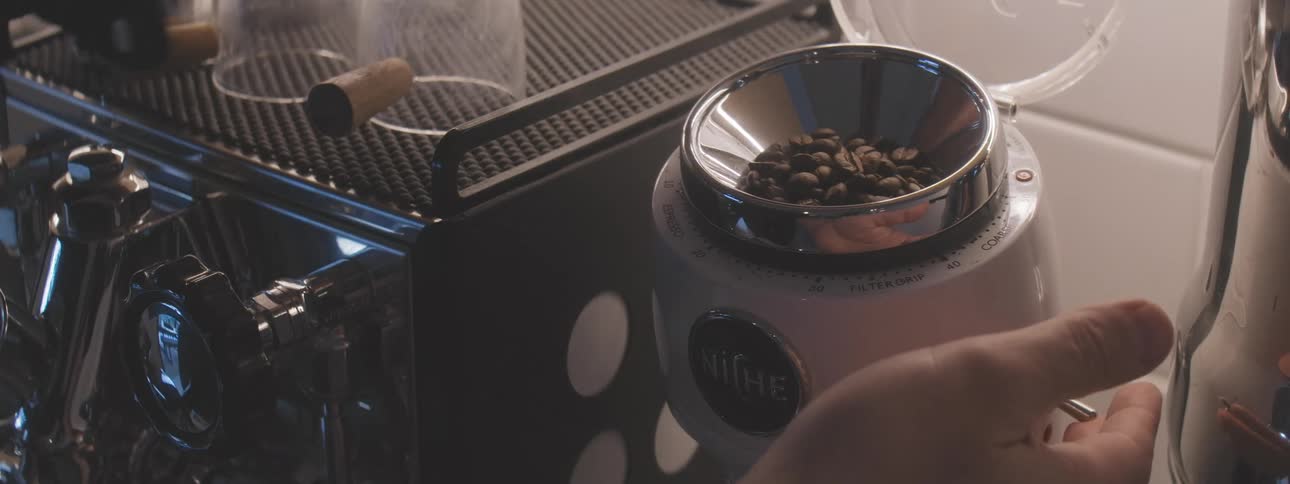 The person crushes beans in the coffee machine