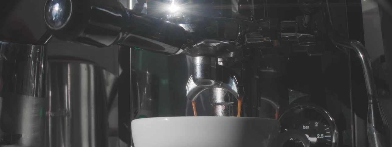Barista making an espresso with a classic coffee machine with steam in background