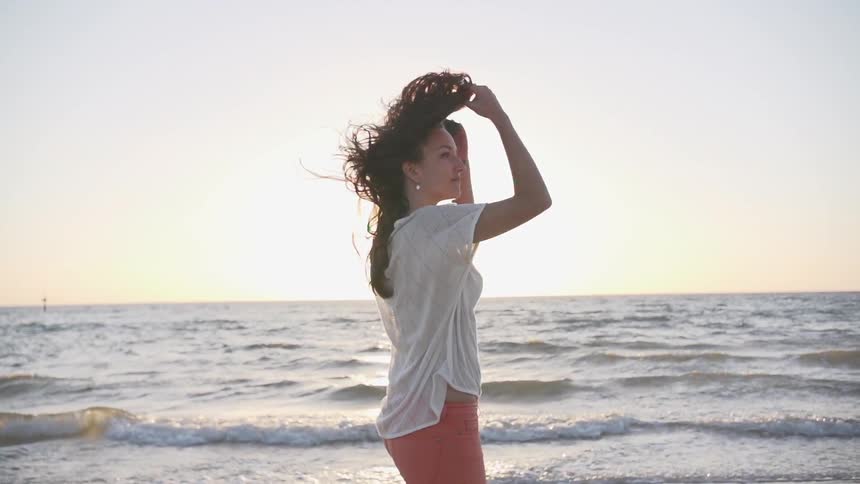 Woman walks on the beach at sunset