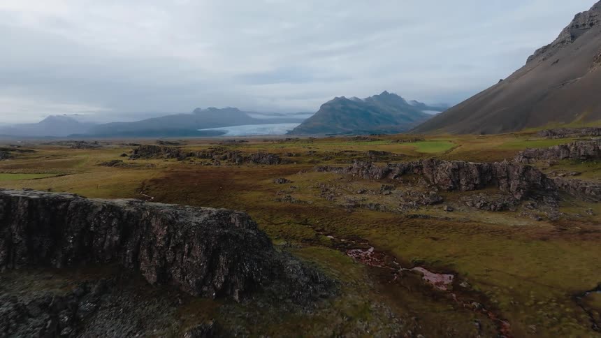 Rocky plain with mountains in the background under a cloudy sky