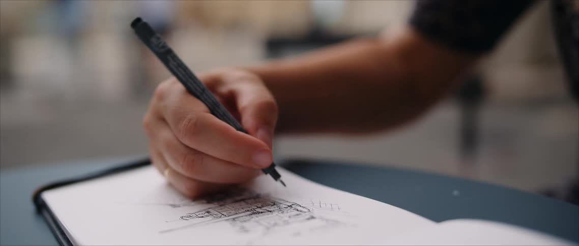 The woman is drawing in her notebook