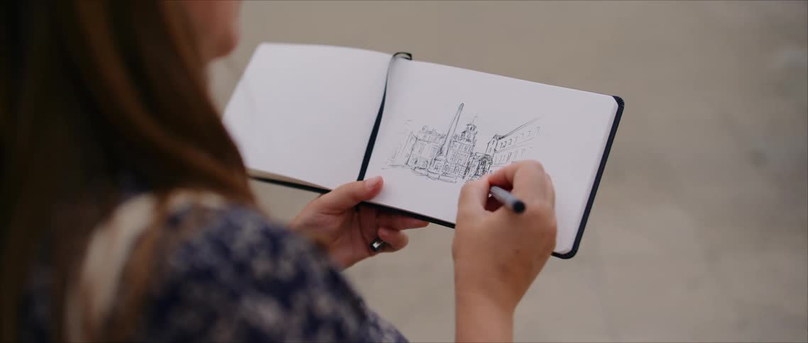 A woman sketches a building