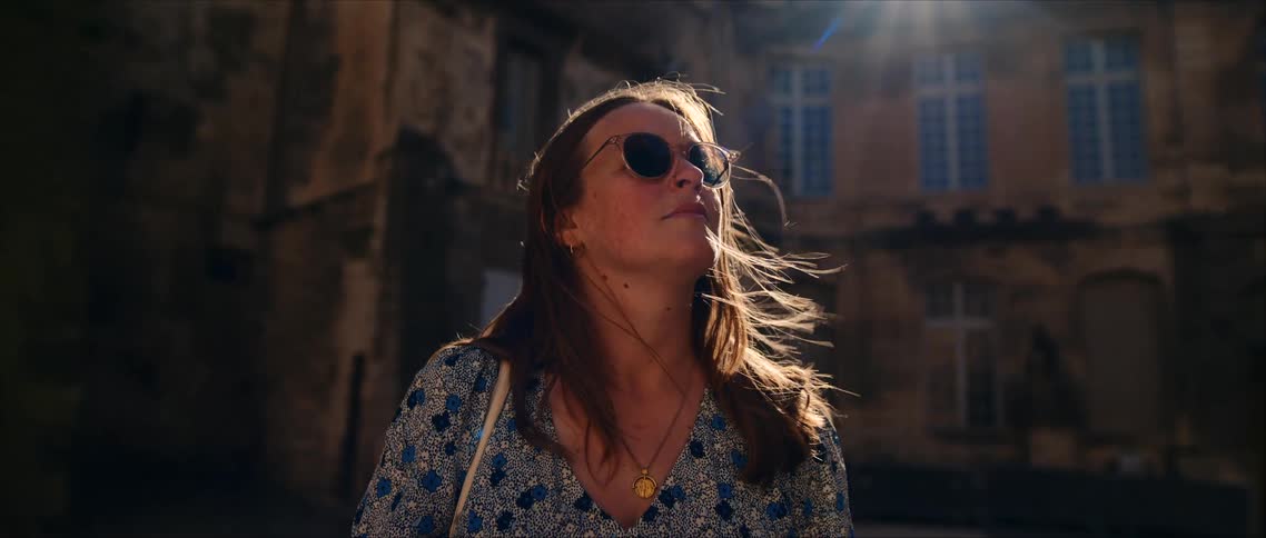 A woman sightseeing near old stone buildings in bright sunlight