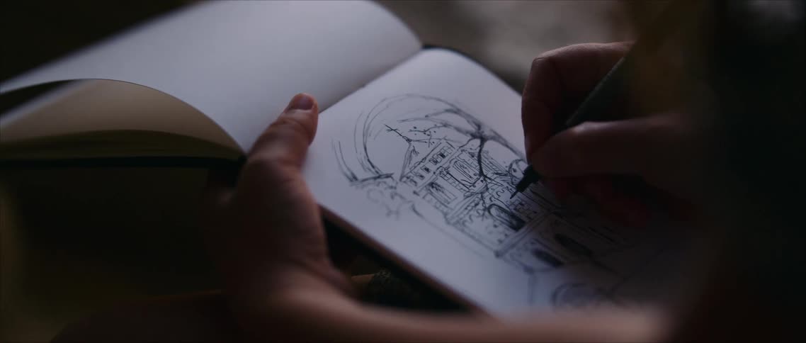 Close up of an artist sketching in a notebook outdoors on a windy day