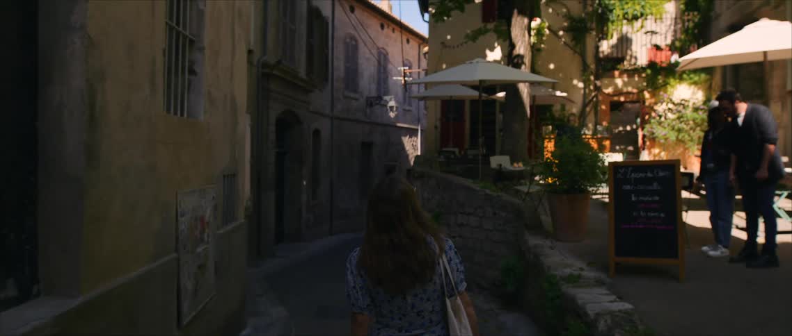 A young woman walking through an alleyway in a town during daytime