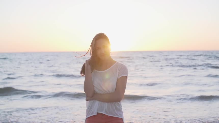 Woman puts her hand to her face near the shore