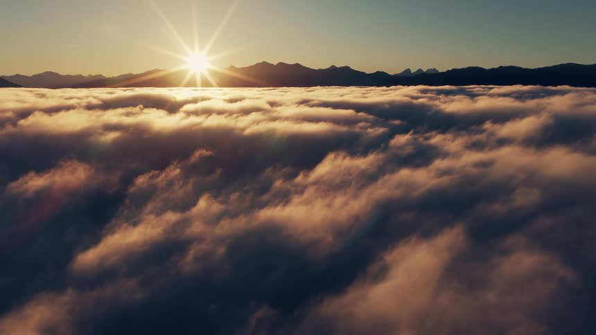 Aerial of bright sun rising on the horizon over the mountains