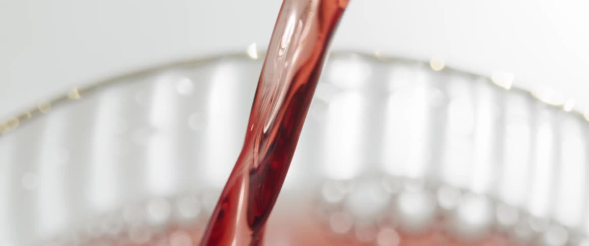 Stream of red juice being poured into a clear glass