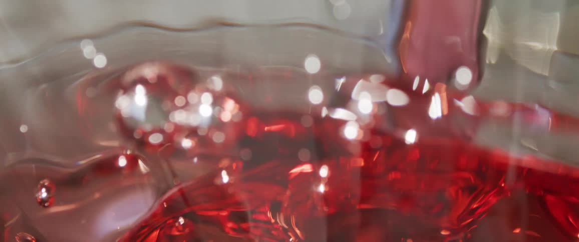 Close up of a red drink pouring into a glass cup